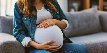 Expectant Woman in Stylish Denim Relaxing on Cozy Sofa, Embracing Joyful Maternity Journey Aheadの素材