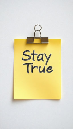 Yellow Sticky Note with Inspirational Message Clamped to Minimal Background for Focus and Motivationの素材