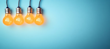 Four Illuminating Light Bulbs Against a Calm Blue Background with Ample Copy Space for Your Ideasの素材