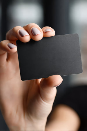 Elegant hand presenting a sleek matte black card, symbolizing luxury and unique opportunity.の素材