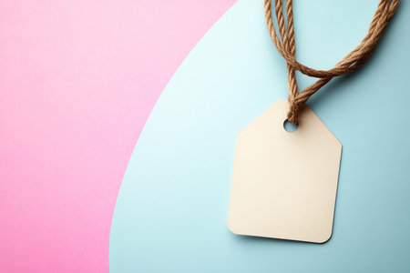 Blank beige tag template with jute hanging on pastel paper background in an elegant style.の素材