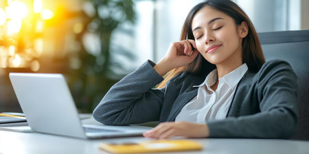 Calm Office Worker Takes a Moment to Relax at Her Desk with Laptop, Embracing Serenity and Focusの素材