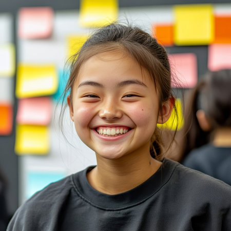 Joyful Asian girl smiling in a colorful workshop, surrounded by sticky notes, teamwork, creativity.の素材