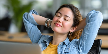 Asian Young Woman with Closed Eyes Sitting at a Desk, Posing Calmly and Taking a Relaxing Breakの素材