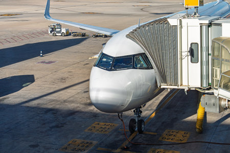 Modern Airplane Docking at Airport Gate Preparing for Passenger Boarding and Departureの写真素材
