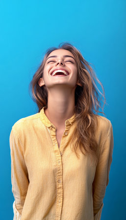 A Joyful Young Woman Laughing with Head Back, Radiating Happiness Against a Clean Blue Backgroundの素材