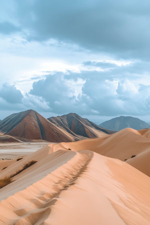 Serene Desert Landscape with Rolling Dunes and Mountains Under a Beautiful Cloudy Sky at Dayの素材