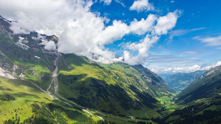 Majestic Alpine Valley Vista Lush Greenery, Towering Mountains, and Dramatic Cloudscapeの写真素材