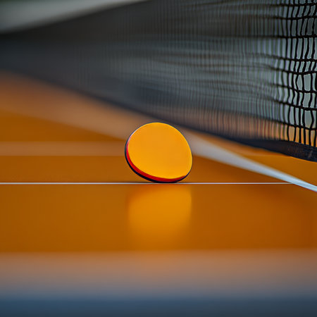 Close-up of an Orange Ping Pong Paddle Isolated by a Net on a Dark Table, Ideal for Sports Themesの素材