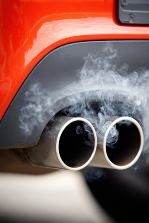 Closeup of Chrome Car Exhaust Pipes Emitting Fumes, Highlighting Automotive Emission and Environmentの素材