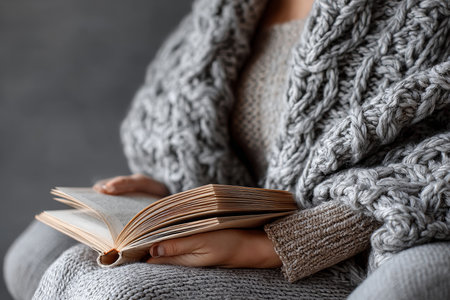 Cozy Moment with an Inspiring Book Cuddled Up in a Warm Cardigan, Immersed in Literary Adventuresの素材