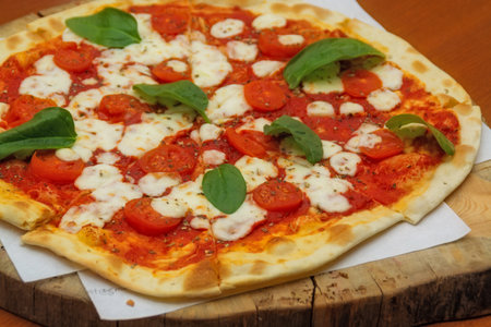 Traditional Margherita pizza with fresh tomatoes and spinach leavesの写真素材