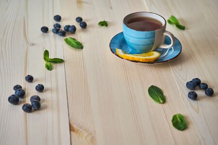 A Cup of tea and blueberries and mint leaves are scattered on the table.の写真素材