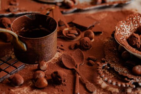 Process of preparation of delicious homemade dark chocolate. Whisk mixer, vintage tableware, ingredients on the table, all covered with cocoa powder. Gourmet dessert. Close up, macroの写真素材