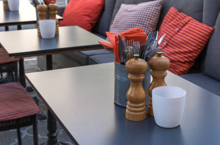 Close Up of Forks Knives Salt Pepper Cellars Table Restaurant Orange Napkinsの写真素材