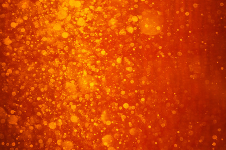 Red - orange background. It is photo of snow fall in night in lantern light. This blurred snowing in warm lights can be a Christmas or winter texture.の写真素材