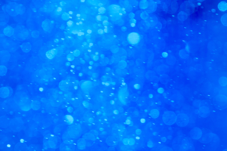 Blue winter background. It is made from photo of real snow fall. This blurred snowing in warm lights can be a Christmas, New Years eve or winter background texture.の写真素材