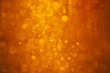 Orange - red - yellow background. It is photo of snow fall in night in lantern light. This blurred snowing in warm colors can be a Christmas or winter background texture.