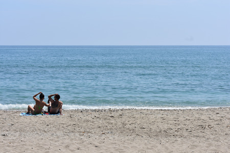 The beach looks blue and has some rocks near the shoreの写真素材