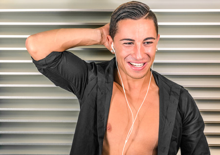 Portrait of a young man listening to music with headphones against a minimal background - Natural expression of happinessの写真素材