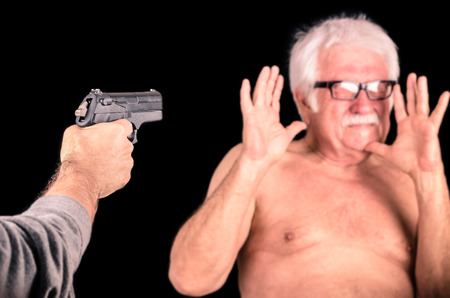 Criminal theratening scared old man with a Gunの写真素材