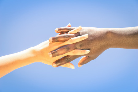 Interracial human hands crossing fingers for friendship and love - Concept of peace and unity against racismの写真素材