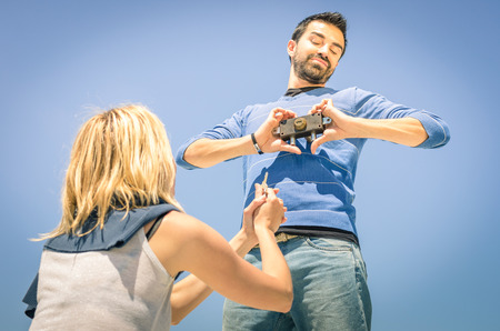 Couple of lovers in a playful attitude - Young woman showing the keys to open the heart padlock of...