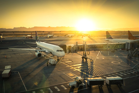 Airplane at the terminal gate ready for takeoff - Modern international airport during sunset - Concept of emotional travel around the worldのeditorial素材