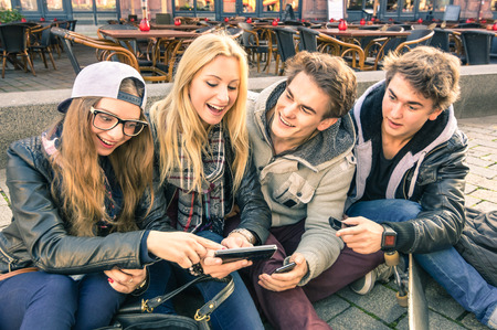 Group of young hipster friends having fun together with smartphone - Modern situation of technology interaction in everyday lifestyle - Internet wifi connection spots outdoors Group of young hipster friends having fun together with smartphone - Modern situation of technology interaction in everyday lifestyle - Internet wifi connection spots outdoors