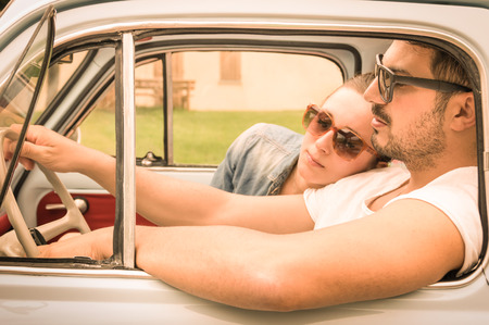 Couple in love having a rest during honeymoon vintage car trip - Hipster lifestyle traveling around the world with classic car - Young people enjoying happy moments of life - Warm retro filtered lookの写真素材