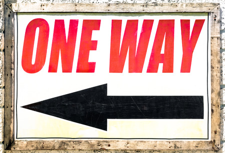 Vintage one way sign with black arrow showing the direction under red lettersの写真素材