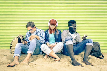 Group of young multiracial friends with smartphone and mutual disinterest towards each other - Social situation of new technology interaction in alienated lifestyle - Vintage nostalgic filtered lookの写真素材