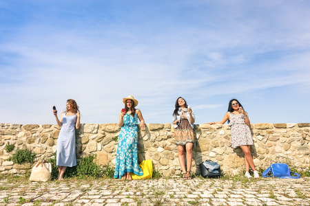 Young women girlfriends using smartphone outdoors with mutual disinterest towards each other  Female modern friendship with technology addiction in actual lifestyle  Sunny afternoon color tonesの写真素材