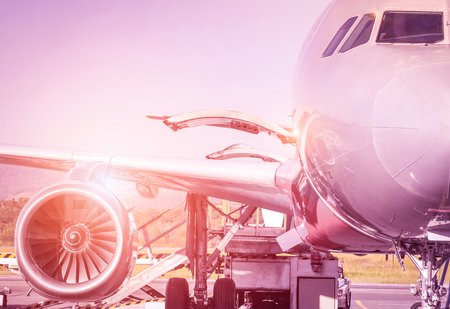 Detail of airplane at terminal gate before takeoff - Travel concept and wander around the world in international airport at sunset - Vintage marsala filtered look with sunshine haloの写真素材