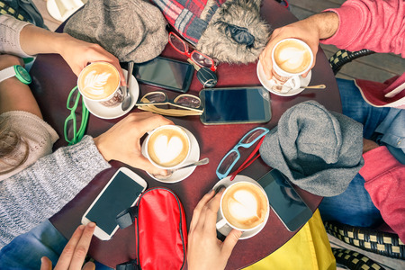 Group of friends drinking cappuccino at coffee bar restaurants - People hands with smartphones with upper point of view - Technology concept with addicted men and women - Soft vintage filterの写真素材