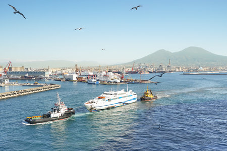 NAPLES, ITALY - NOVEMBER 2, 2015: aerial view of Napoli industrial skyline and Vesuvius with tugboat towing a shipwreck in to city harbour of capital in region Campaniaのeditorial素材