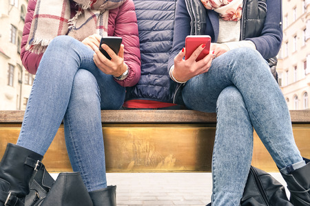 Close up of couple of girlfriends in disinterest moment with mobile smart phones - Concept of relationship apathy sadness and isolation using new technology - Female friends with smartphone addictionの写真素材