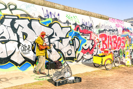 BERLIN, GERMANY - 1 MARCH 2016: street artist performing guitar solo at East Side Gallery near Warschauer Strasse in neighborhood of Friedrichshain Kreuzberg district of the capital city of Germanyのeditorial素材