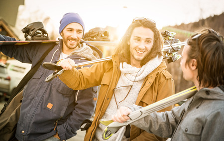 Best friends having fun together walking with ski and snowboard at mountain trip - Friendship...