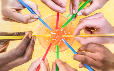 Multiracial friend hands drinking Sex on the Beach cocktail on bucket mug liter - Friendship and fun summer concept with young fancy people having drunk fun at travel vacation - Warm saturated filterの写真素材