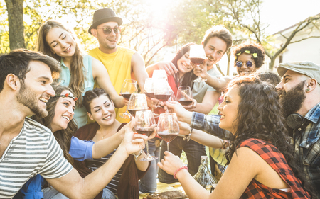 Group of friends toasting red wine having fun outdoor cheering at bbq picnic - Young people enjoying summer time together at lunch garden party - Youth friendship concept - Focus on clinking glassesの写真素材