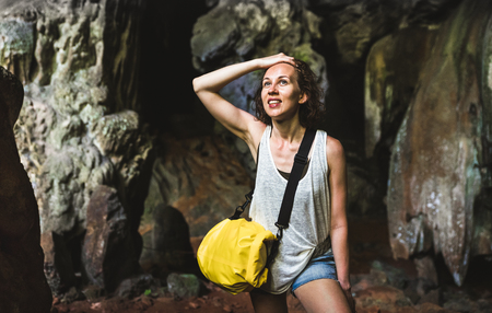 Young woman traveler at cave entrance on island hopping in Cheow Lan Lake - Wanderlust trip and travel concept with adventure girl tourist wanderer on excursion in Thailand - Warm contrast filterの写真素材