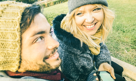 Happy couple in love enjoying time outdoor on winter cloth - Handsome man and young woman talking and having fun together - Relationship concept with boyfriend and girlfriend on bright greenery filterの写真素材