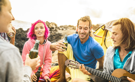 Hipster friends having fun together at beach camping party - Friendship travel concept with young...