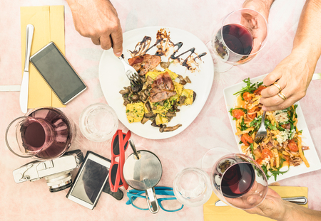 Top view of senior couple hands eating food and drinking wine at fashion restaurant - Retired people enjoying ravioli pasta and seasonal salad at travel break - Lunch and dinner concept outdoorsの写真素材