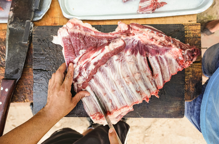 Butcher cutting ribeye t-bone steak - International food concept with hand preparing raw fresh beef meat at table in butchery laboratory - Sirloin fillet with bones ready to be cooked at kitchenの写真素材