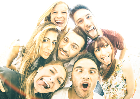 Happy best friends taking selfie outdoors with backlighting - Friendship concept with young people...