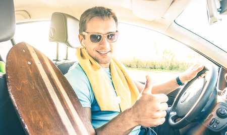 Young hipster fashion model guy driving car with longoboard on spring break summer mood - Happy...