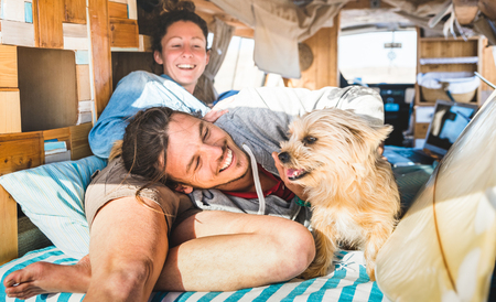 Hippie couple with funny dog traveling together on vintage minivan transport - Life inspiration concept with indie people on mini van adventure trip in relax moment - Bright warm retro filterの写真素材