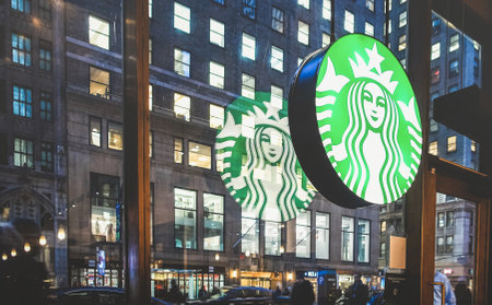 NEW YORK - MARCH 25, 2015: Starbucks sign at cafe shop by night with glass reflections on Nyc nightscape - The enterprise is an american coffee company and coffeehouse chain founded in 1971のeditorial素材